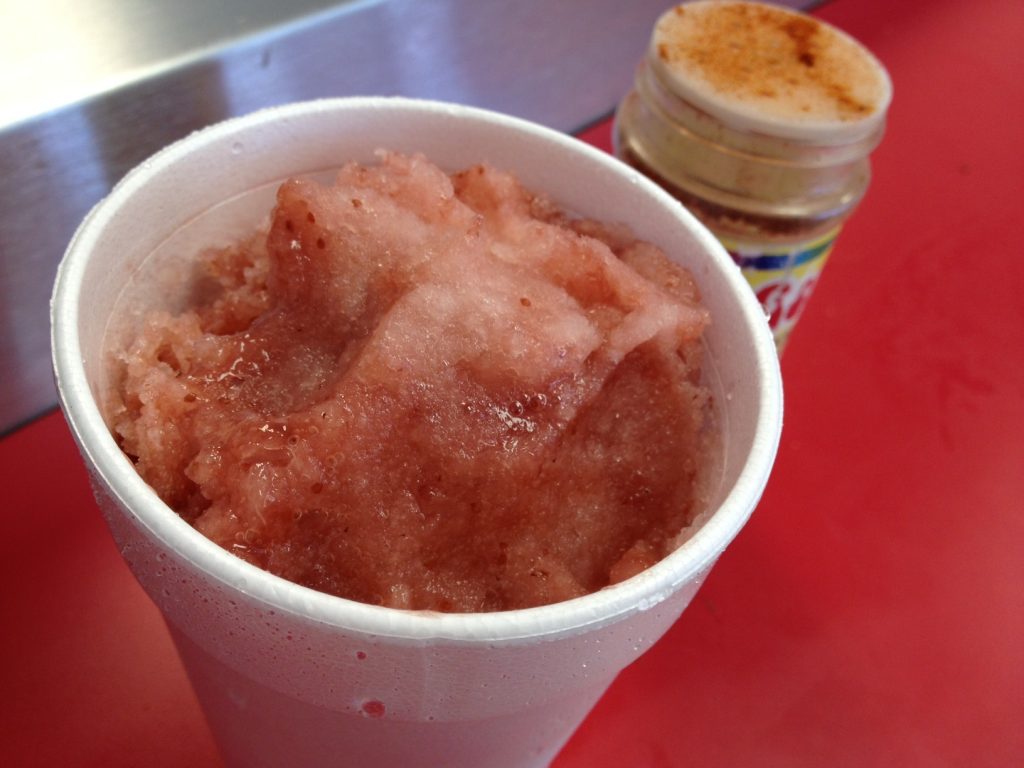 Natural strawberry-lime sno cone at Sno. Chile (pictured at back) and salt are available for sprinkling on top.