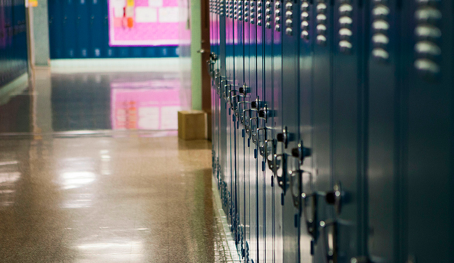 A series of lockers in a high school hallway. The lockers are all locked and closed.